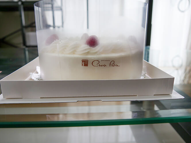 白い箱と同じ高さの透明カバーでケーキを保護してある